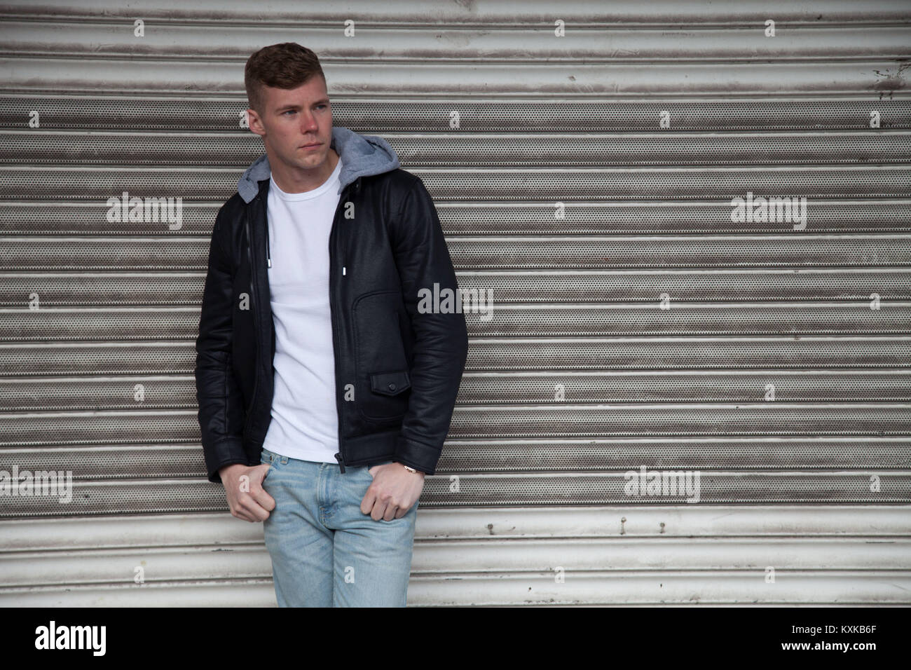 Gut aussehende, blonde männliches Modell lehnte sich auf shop Fensterläden in verlassenen Einkaufszentrum Stockfoto