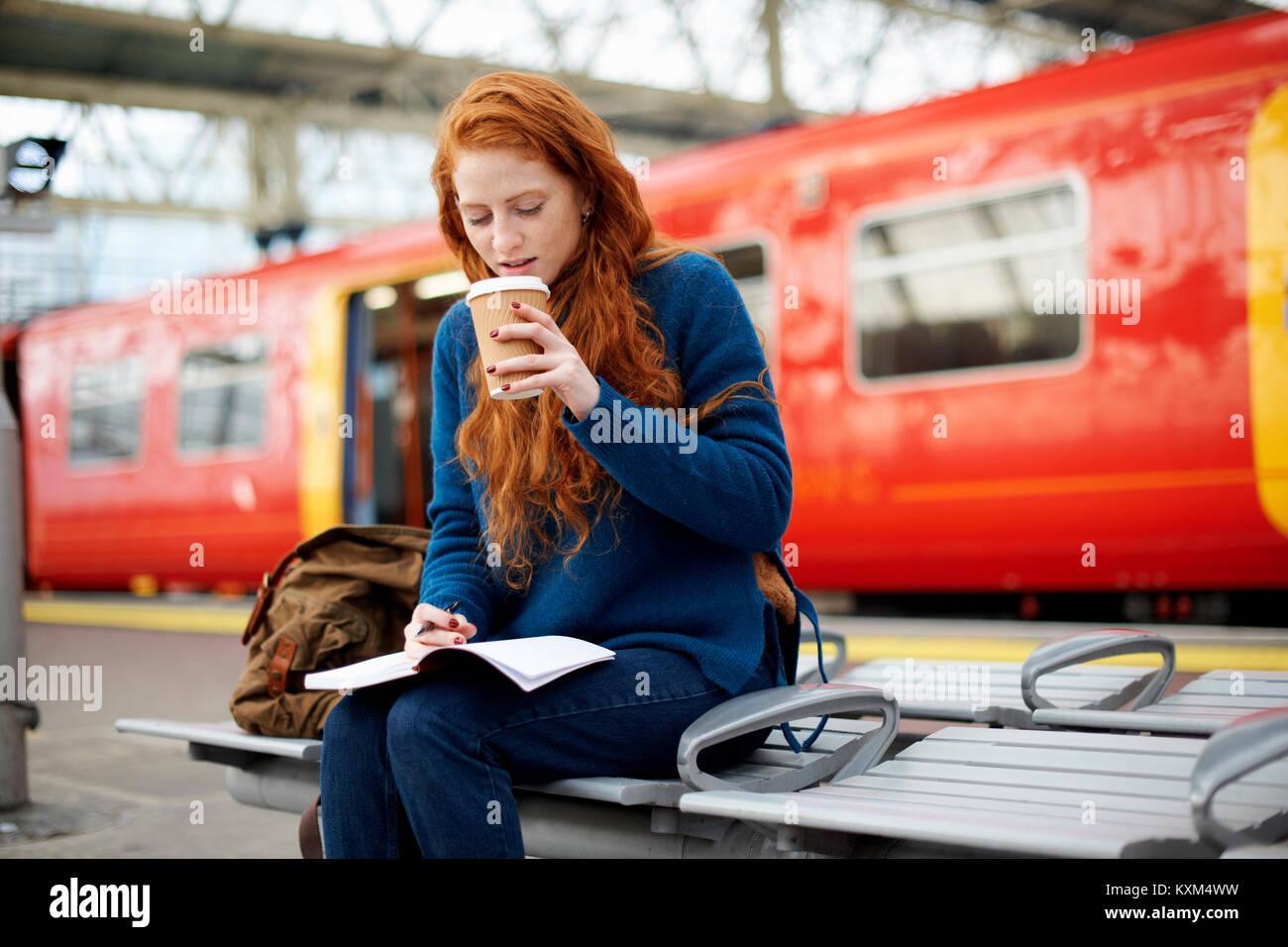 Frau auf der Bank am Bahnsteig, London Stockfoto