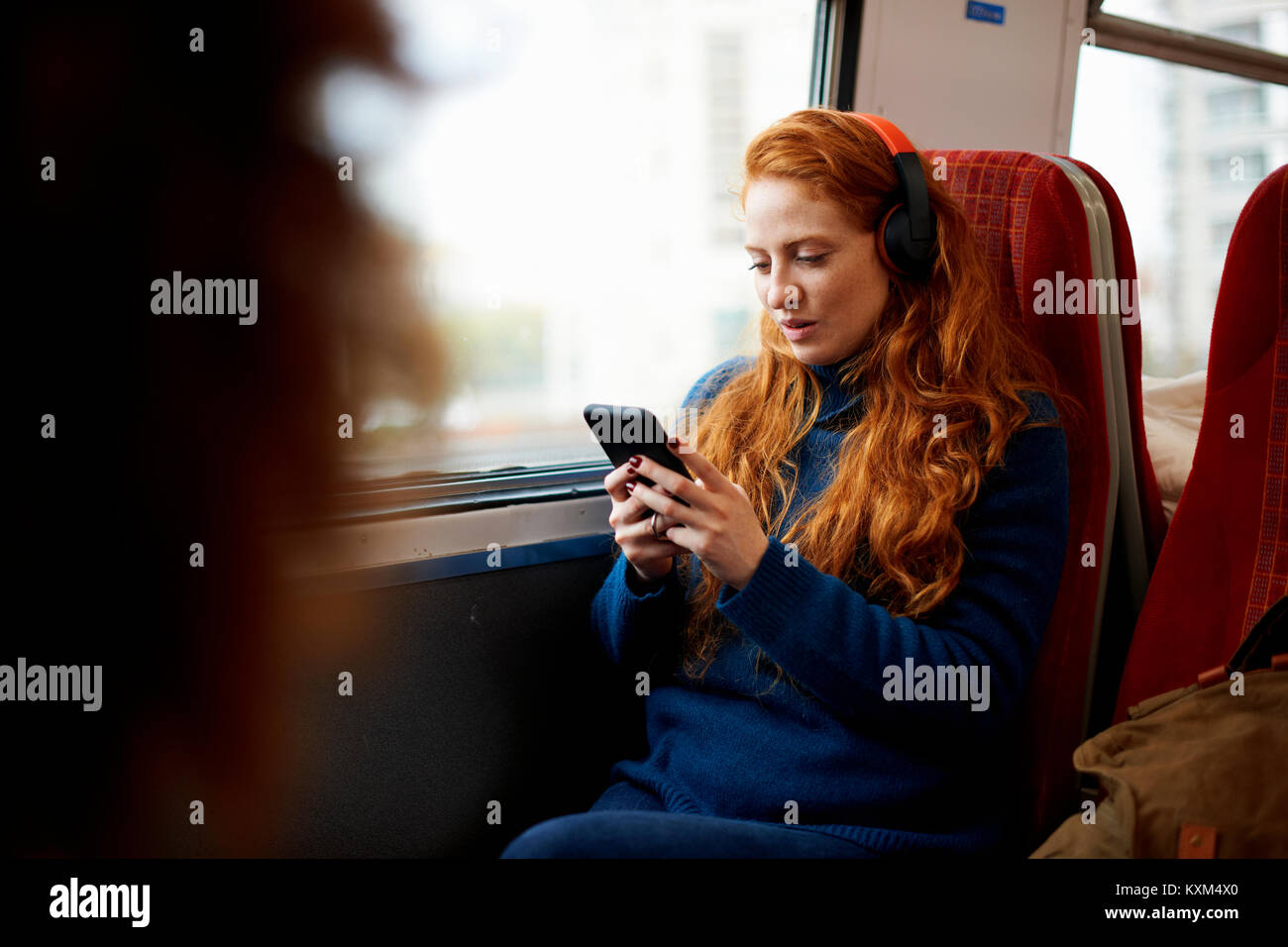 Frau auf dem Zug hören die Musik auf Handy mit Kopfhörer, London Stockfoto