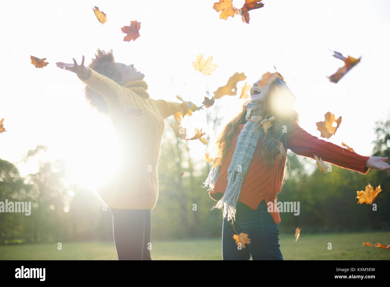 Freunde werfen Blätter im Herbst in der Luft Stockfoto