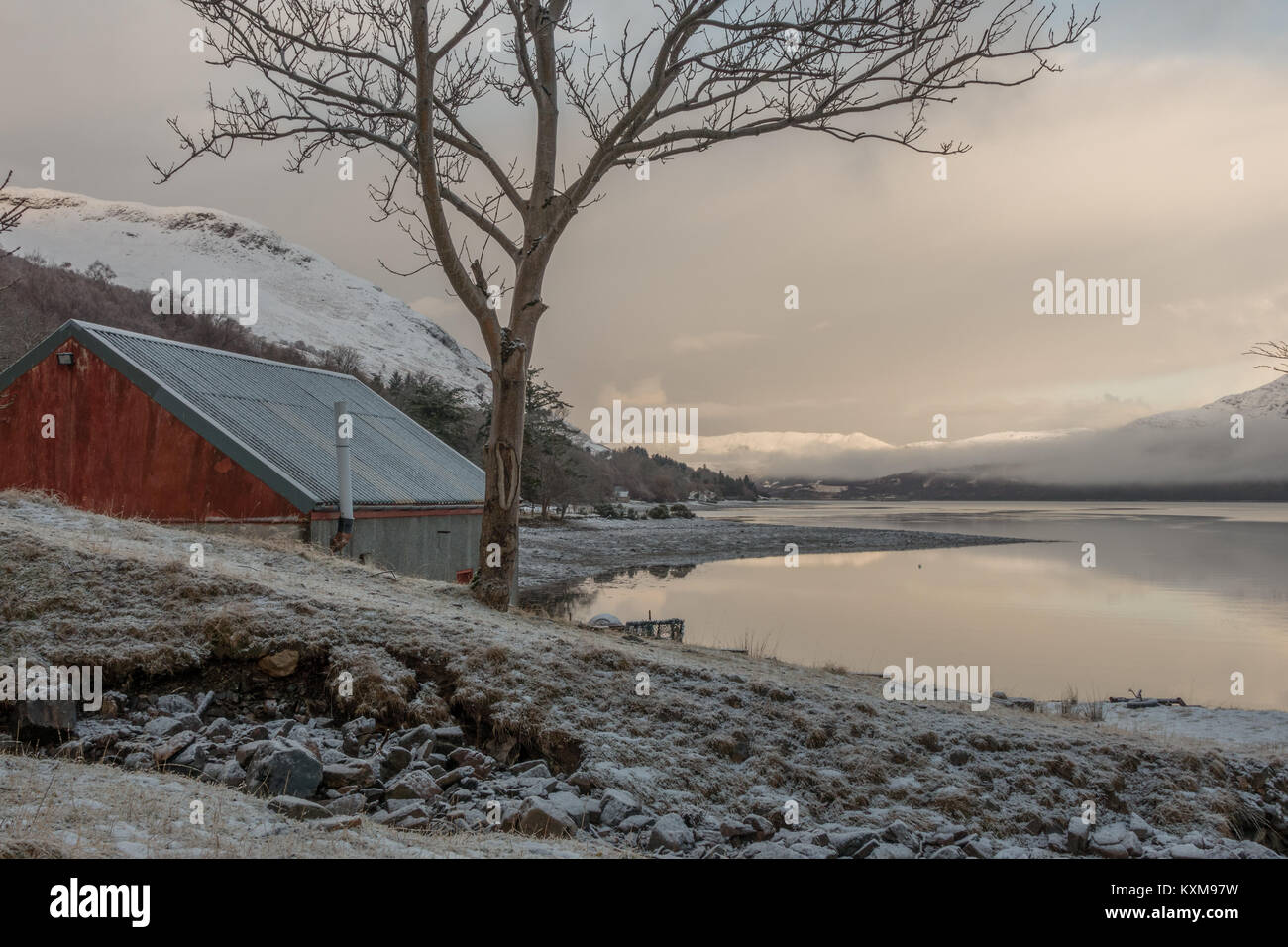 Blick über Loch Broom auf die verschneiten Berge vom verschneiten Ufer und das Bootshaus an Buchstaben, Ullapool, Scottish Highlands, Schottland Stockfoto