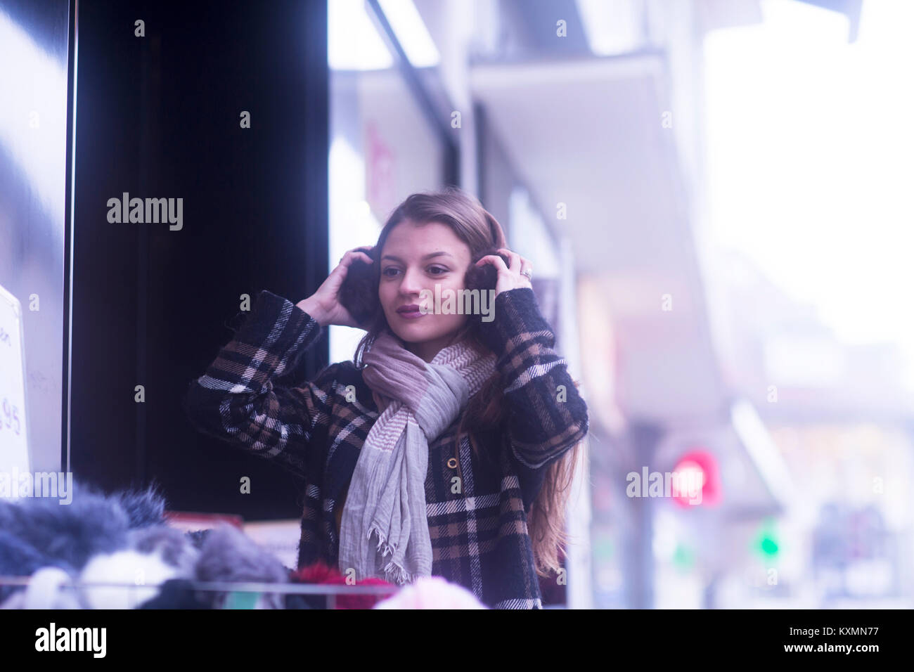 Frau shopping, die versuchen, auf Ohrenschützer Stockfoto