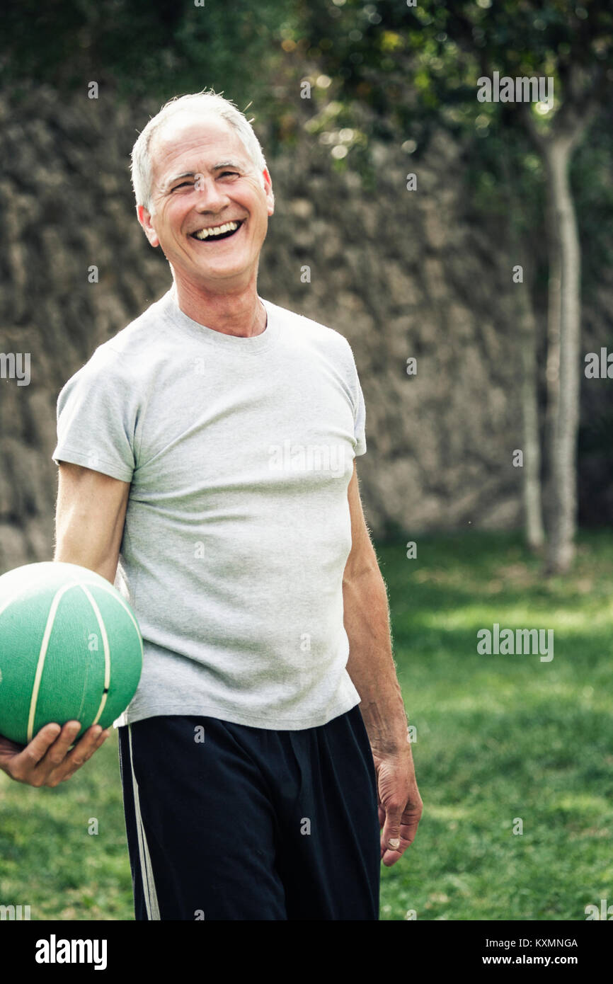 Porträt der Mann hält Basketball an der Kamera schaut lächelnd Stockfoto