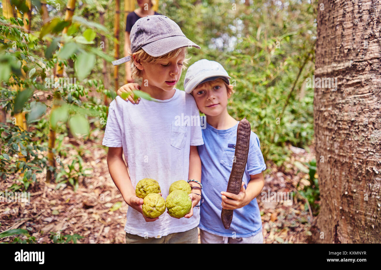Jungen im Dschungel holding Kokosnüsse und Saatgut, Aguas Calientes, an das Departamento Chuquisaca, Bolivien, Südamerika Stockfoto