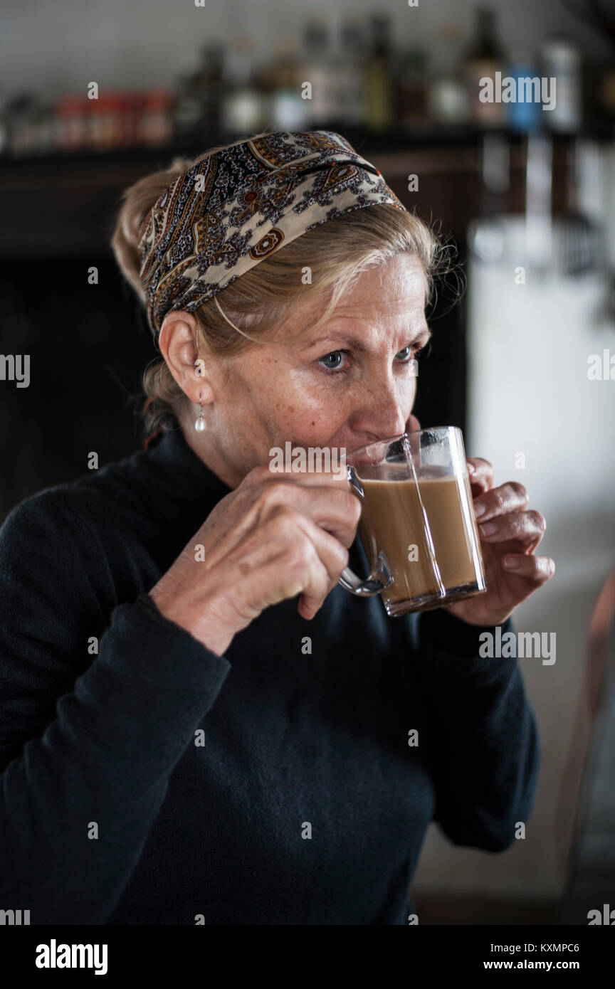 Blonde ältere Frau trinkt Kaffee in der Küche Stockfoto