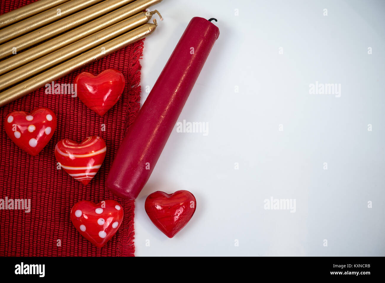 Kleine rote Herzen Tierfiguren aus Glas, rot und gold Kerzen auf weißem Hintergrund Stockfoto