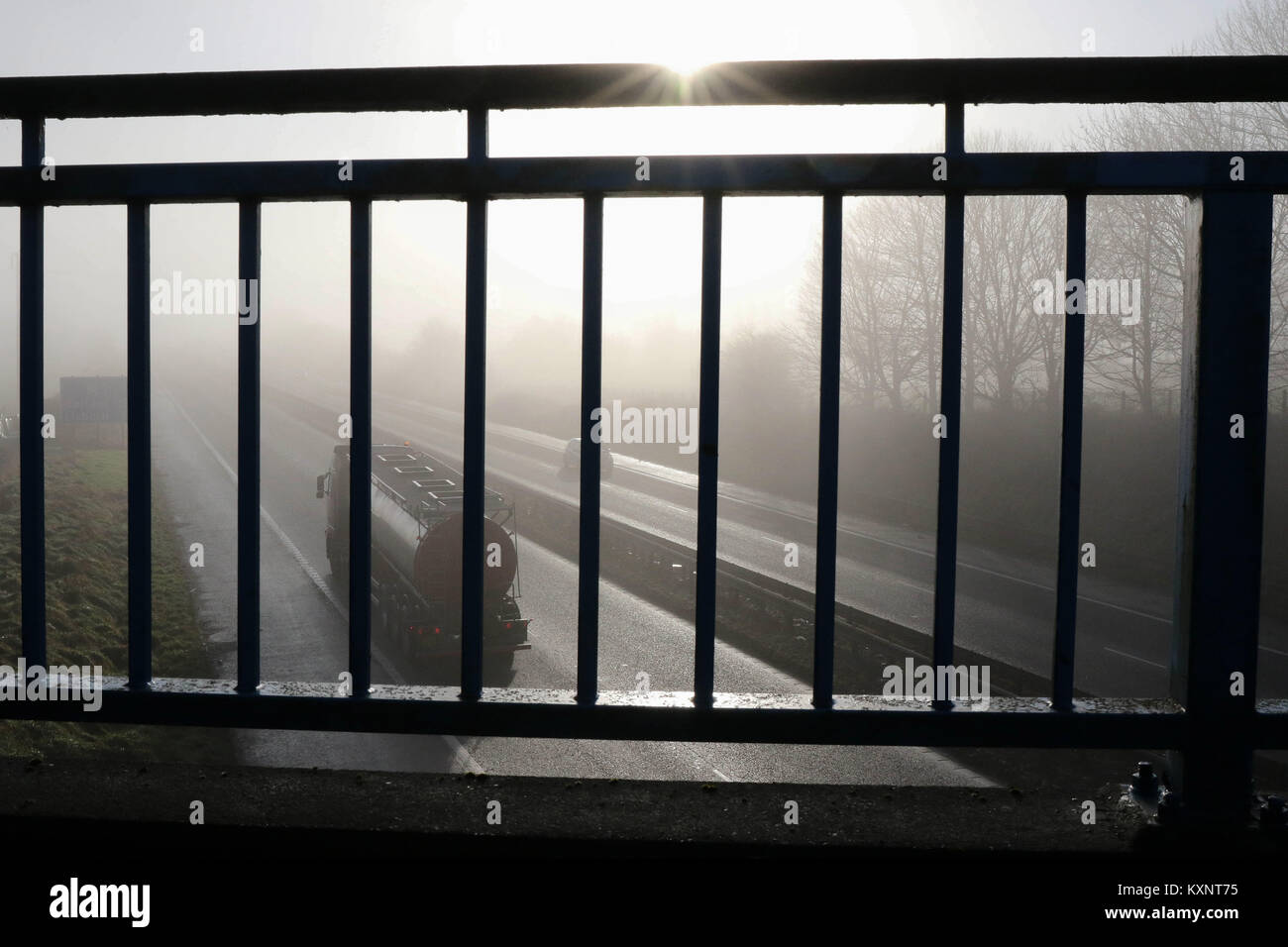 County Down, Nordirland. 11. Januar 2018. Wetter im Vereinigten Königreich – nach starkem Nebel über Nacht blieb in Nordirland bis heute (Donnerstag) um 11am Uhr eine Nebelwarnung bestehen. Während die Sonne durchbrach, kehrte der Nebel den ganzen Tag über regelmäßig zurück. Aufgrund der eingeschränkten Sicht wurde in Teilen des Landes eine Höchstgeschwindigkeit von 40 km/h auf der Autobahn festgelegt. Autobahnverkehr, der durch Nebel auf der Autobahn M1 in Nordirland fährt, während die Sonne durchbricht. BHZ.Credit: CAZIMB/Alamy Live News. Stockfoto