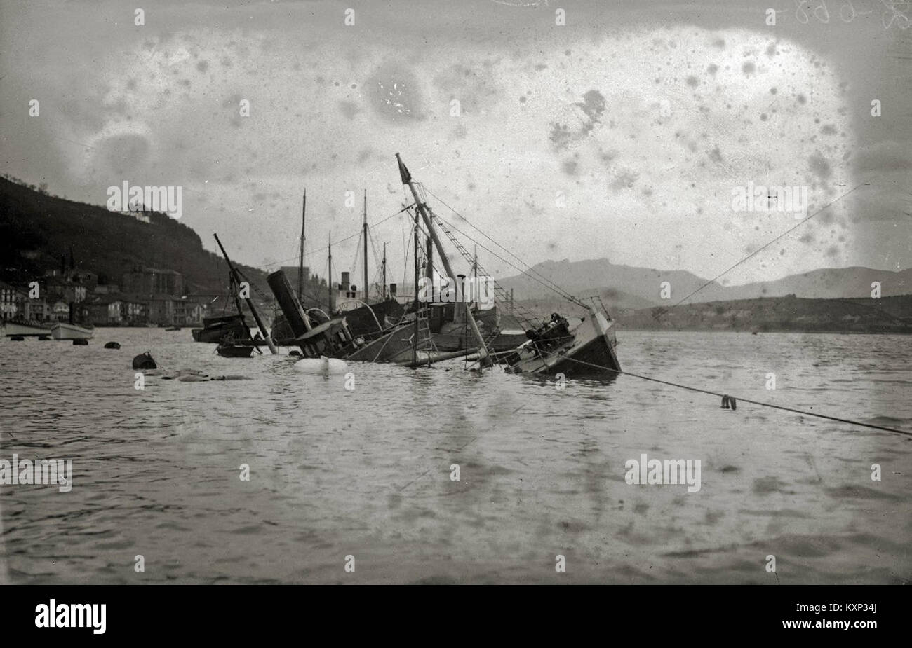 Das Wrack des „Almike“-Schiffes im Hafen von Pasaia ist auf einem historischen Foto festgehalten, das die Seeschäden und ihre Auswirkungen auf die lokale Hafengemeinschaft zeigt. Stockfoto