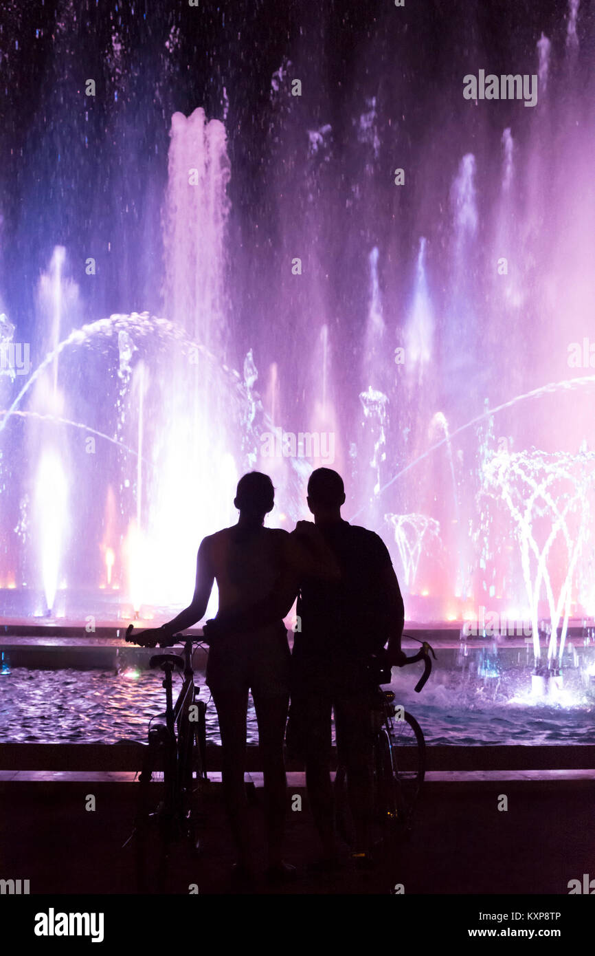 Hugging Paar beobachten Farbe Brunnen Show am Abend Stockfoto