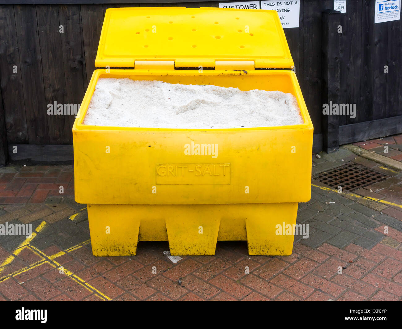 Ein grosses gelbes Kunststoffbehälter mit Salz und Splitt für entfrosterschalter und die Verringerung der Gefahr der gefährlichen rutscht aus und fällt in einen Parkplatz Stockfoto