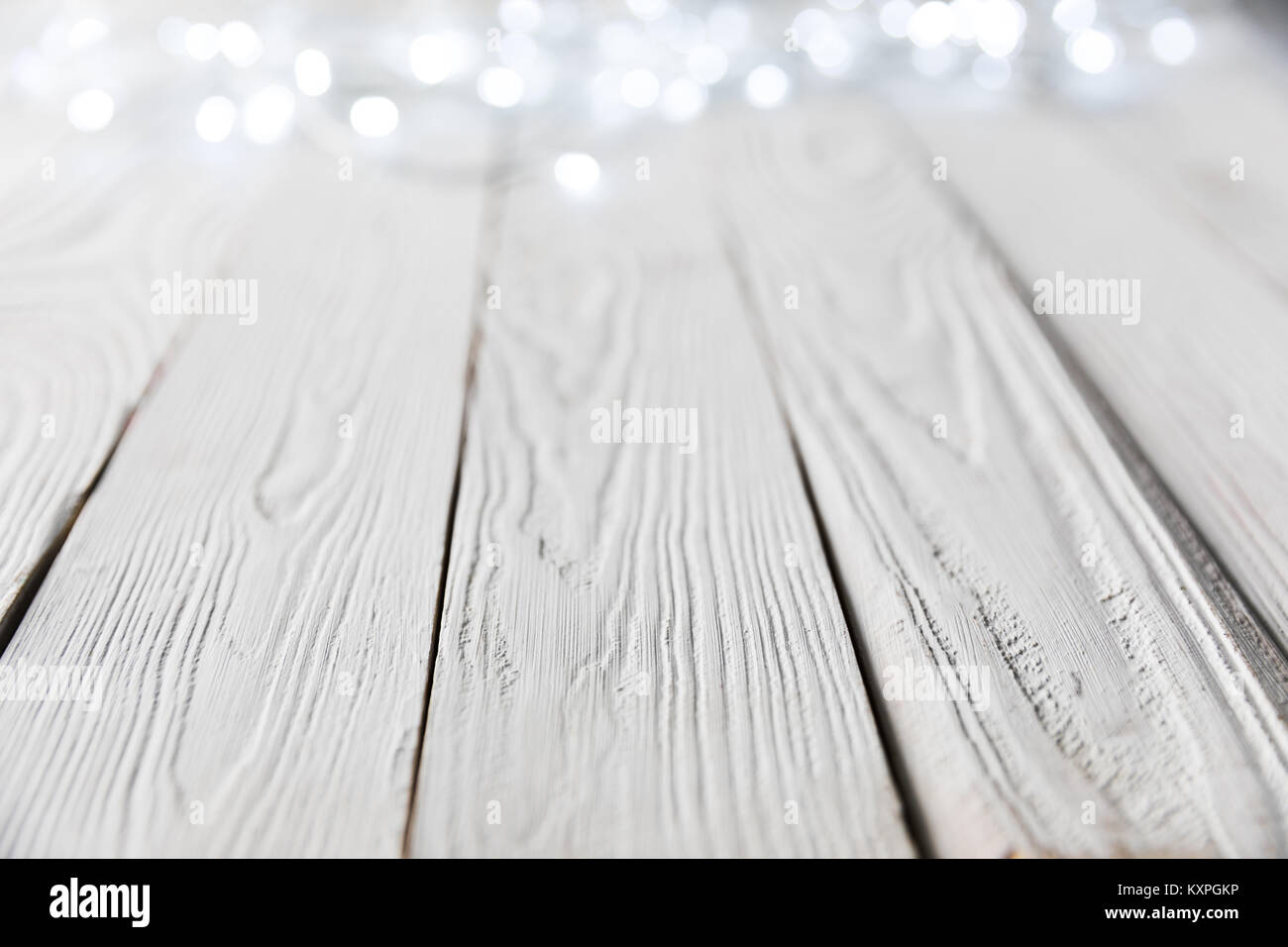 Festliche Weihnachten bokeh leuchtet auf weißem Holz- Oberfläche Stockfoto