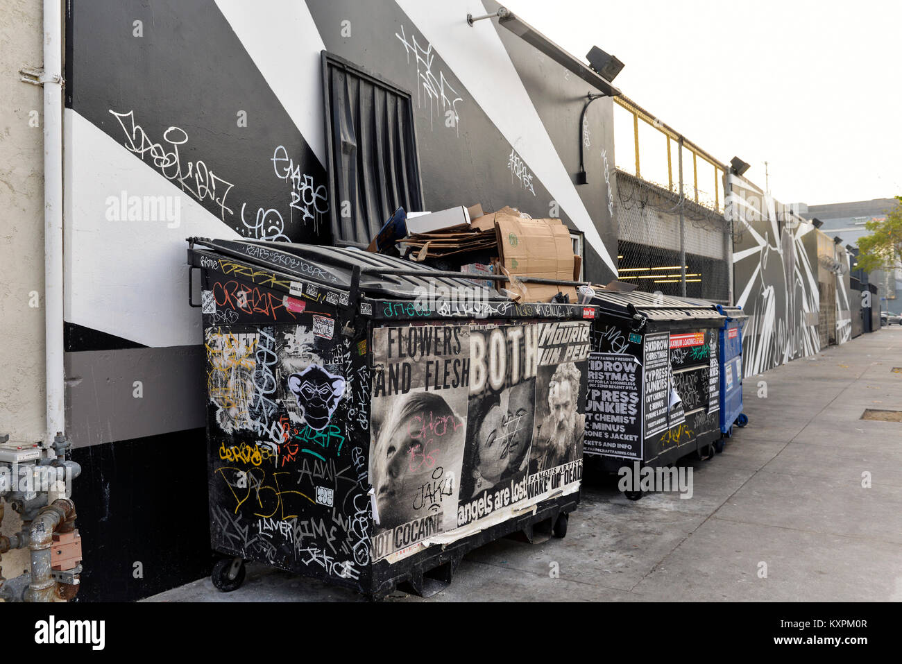 Künstlerische graffiti auf einer Gasse Wand- und Papierkorb Müllcontainer im Arts District, Downtown, Los Angeles, Kalifornien. Stockfoto