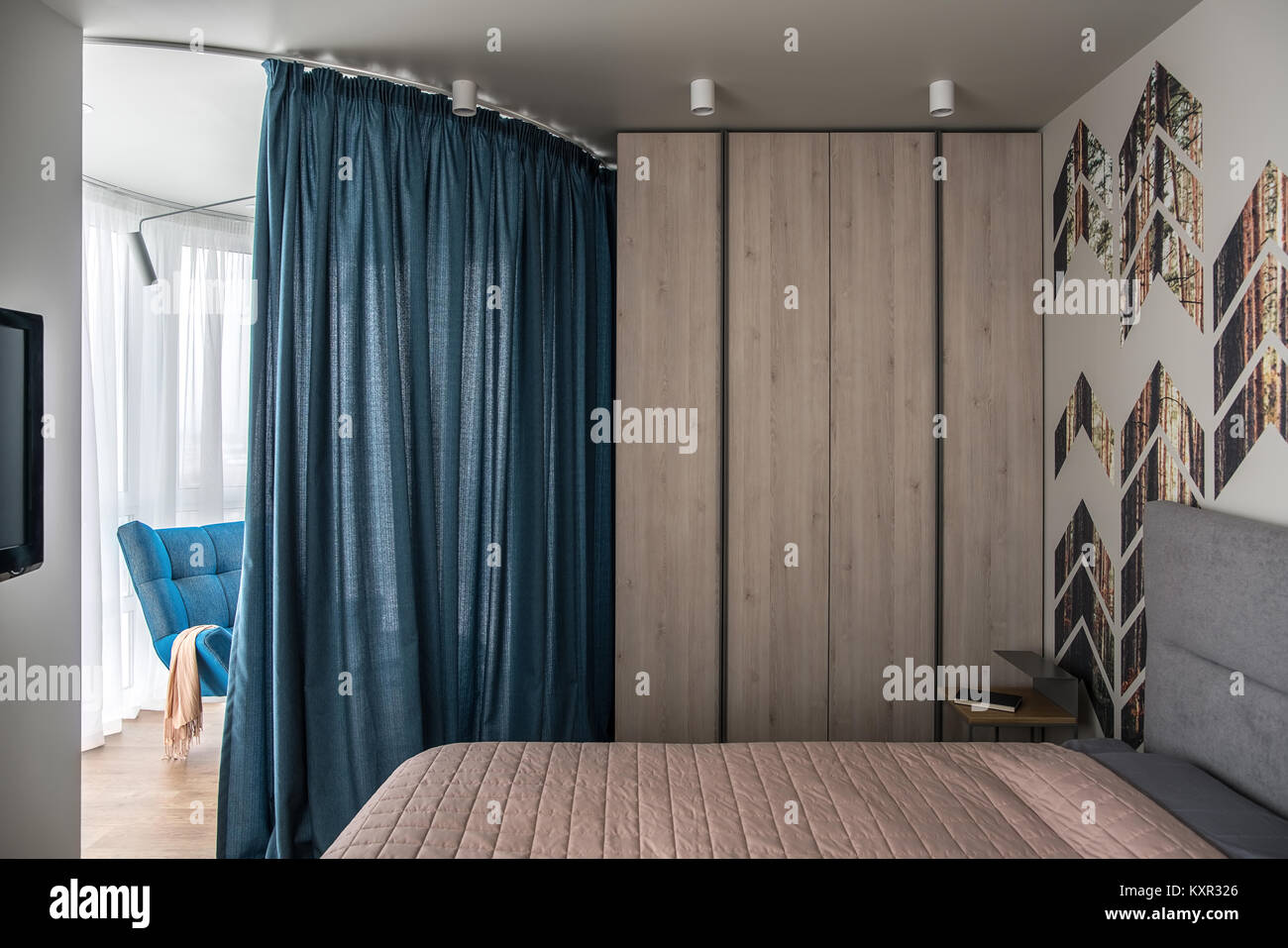 Modernes Schlafzimmer mit einem bunten Wand mit Kiefer gedruckt wird. Es gibt ein Bett mit einer Bettdecke und Kissen, Nachttisch mit einem Buch, Spind, Zone B Stockfoto