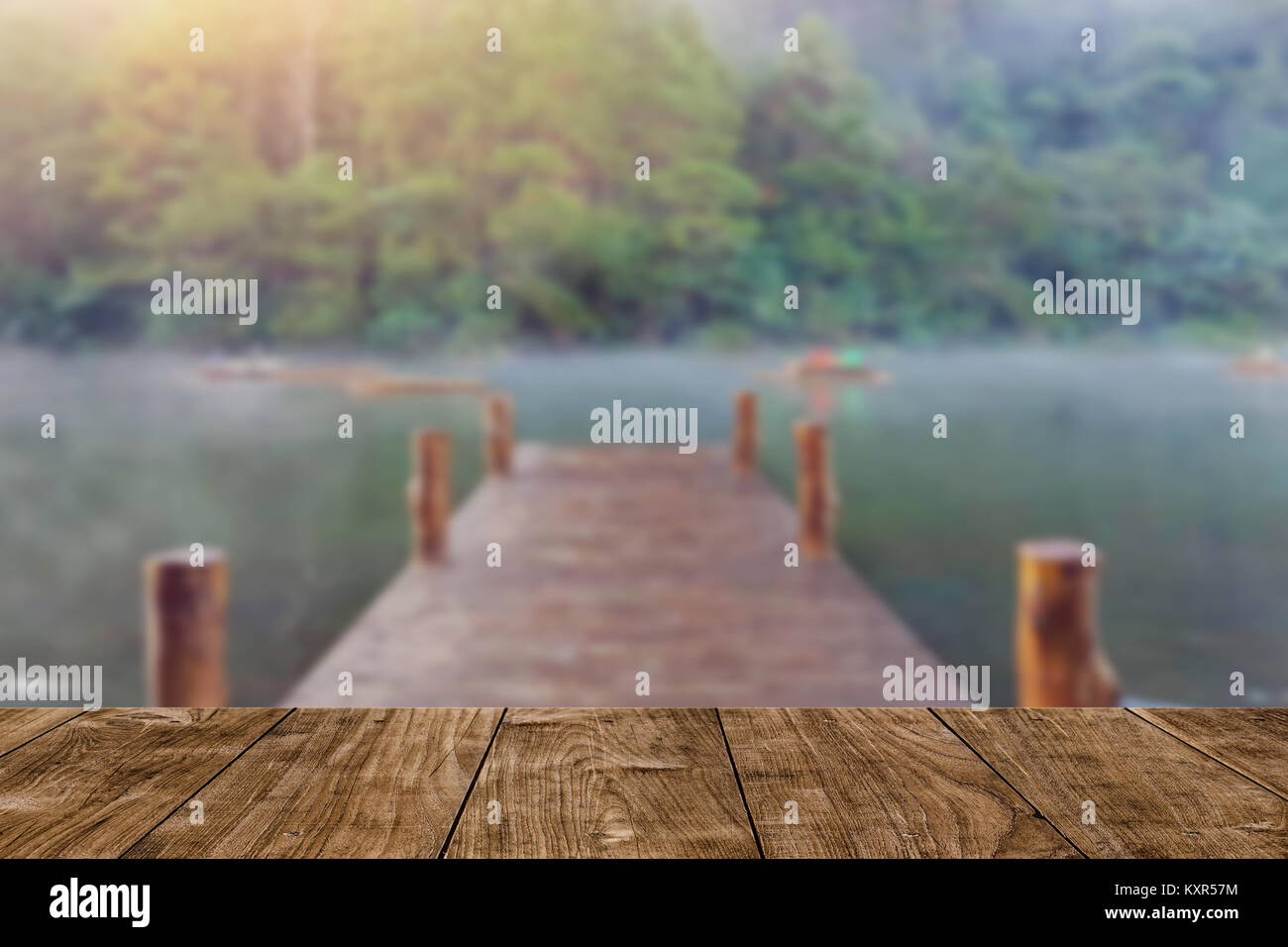 Holz Tisch mit blur Holz Brücke dock See im Wald Hintergrund Stockfoto