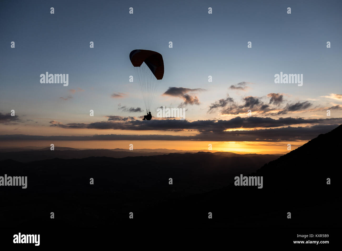 Schöne aufnahme eines Gleitschirms silhouette Fliegen über Monte Cucco (Umbrien, Italien) mit Sonnenuntergang im Hintergrund, mit schönen Farben und dunklen Töne Stockfoto