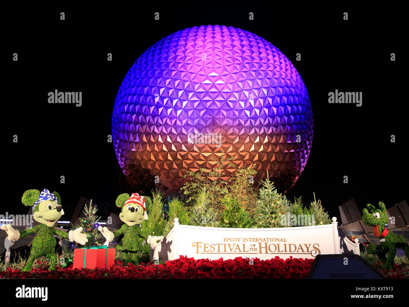 Disney's Epcot Center Bereich bei Nacht beleuchtet während der Ferien Saison mit Mickey Mouse, Minnie und Pluto Zeichen gras Skulpturen. Stockfoto