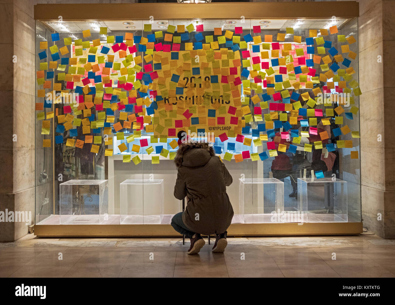 Eine Frau, die ihre neue Jahre '18 Auflösung auf einem stickie Hinweis & Buchung es auf dem Fenster der Gift Shop der wichtigsten Filiale der öffentlichen Bibliothek Stockfoto
