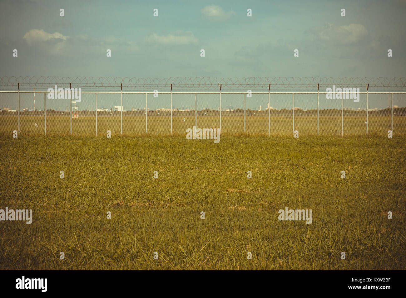 Green Field und Stacheldraht zaun im Gefängnis oder Sicherheitszone, vintage Foto und Film Stil Stockfoto