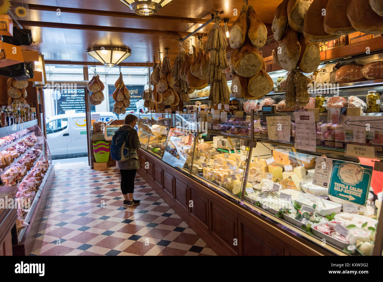 Eine Frau in Essen suchen auf Anzeige insode Eine traditionelle italienische Feinkost, Käse, Schinken und Otaly charcutterie in Bologna Stockfoto