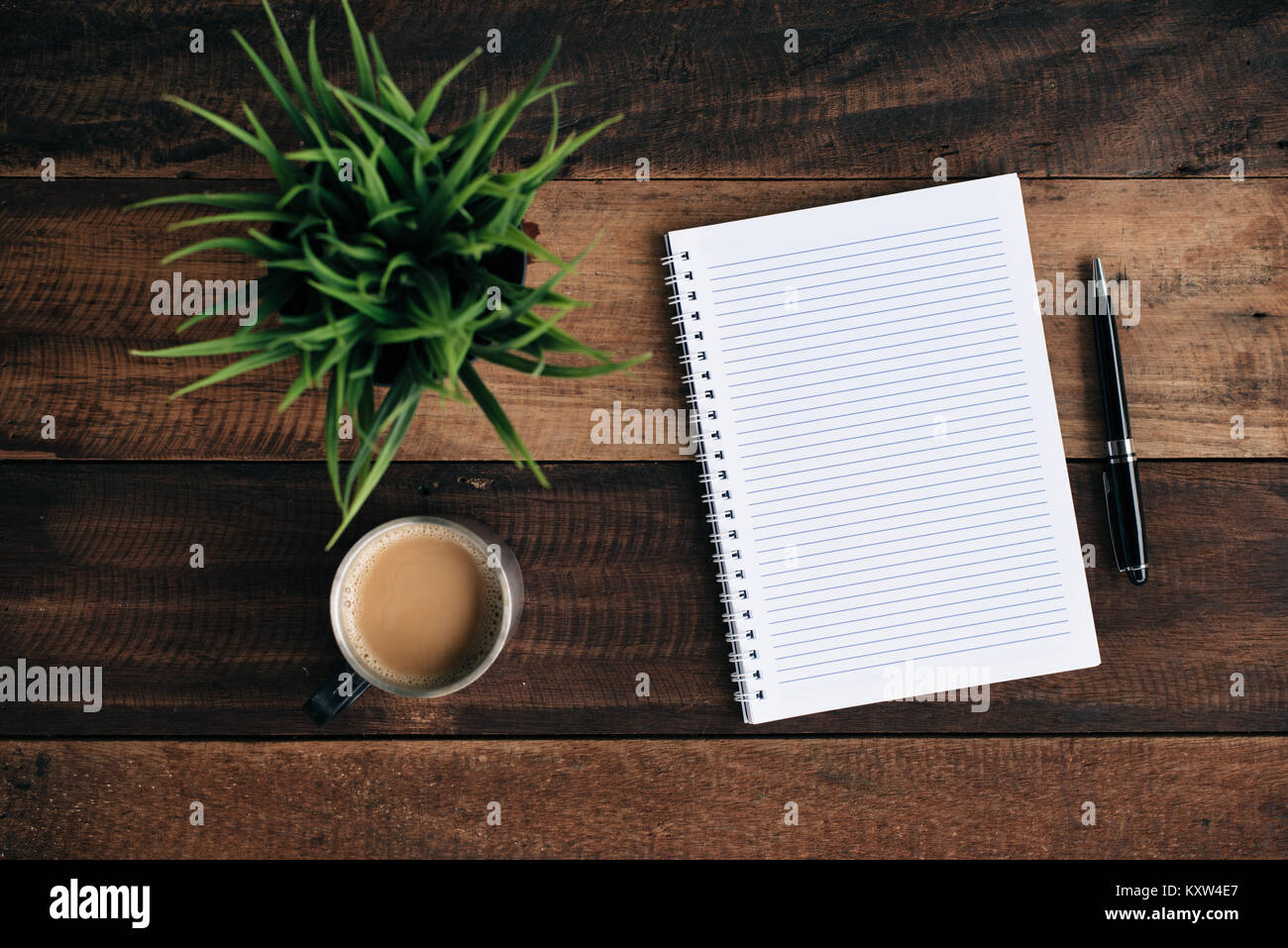 Kaffee, Gläser Kugelschreiber, grüne Pflanze und leeren Notebook auf Holztisch. Flach Top View Stockfoto