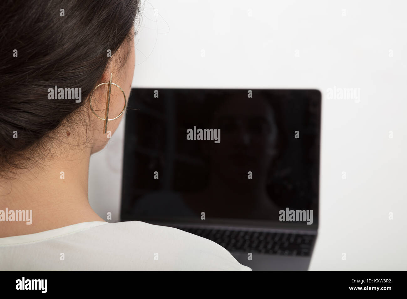 Blick über die Schulter einer Frau mit einem Laptop mit schwarzen Bildschirm für Kopie Raum gegen grauer Hintergrund Stockfoto