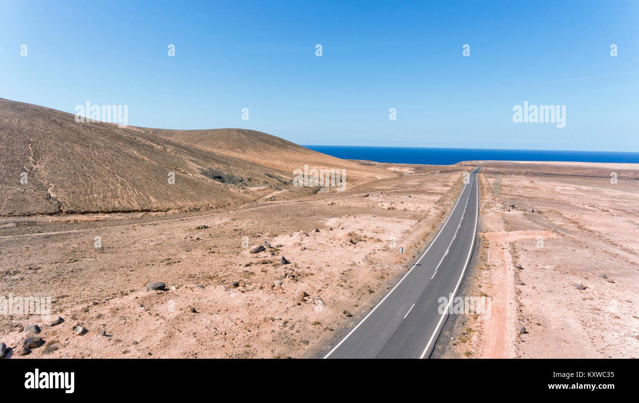 Luftaufnahme der lange Weg durch die vulkanische Landschaft der Wüste in Richtung Atlantik, Fuerteventura, Kanarische Inseln, Spanien. Stockfoto