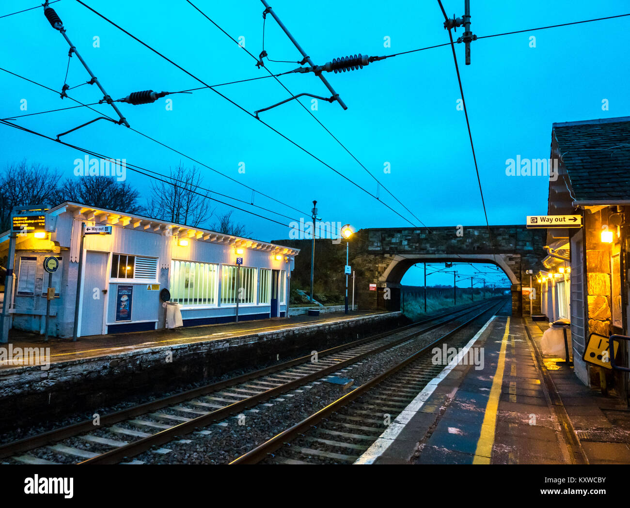 Drem Bahnhof, East Lothian, Schottland, Großbritannien, in der Abenddämmerung mit Licht auf und weg aus Zeichen leuchtet Stockfoto