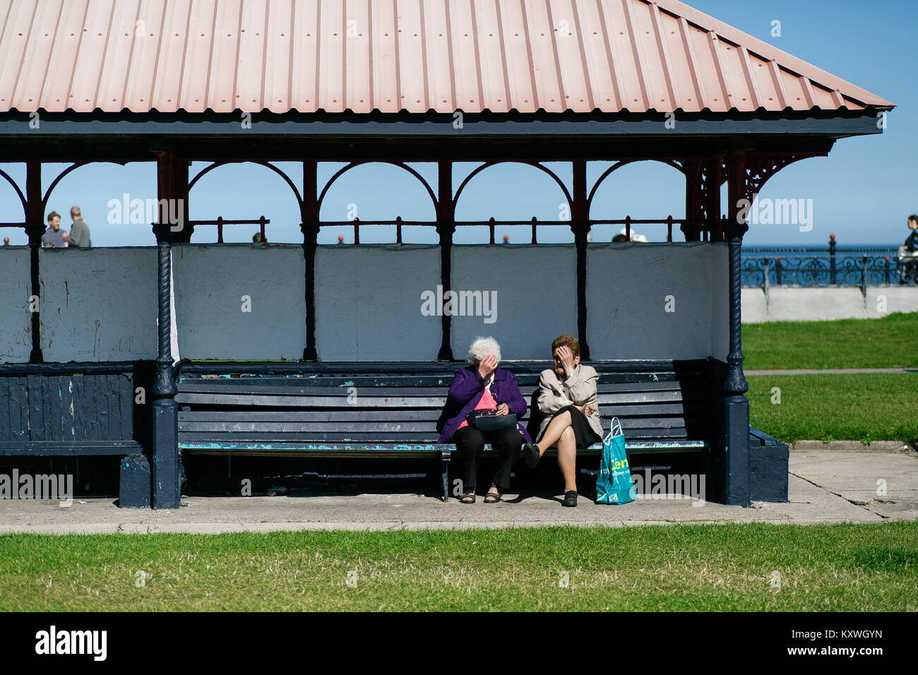 Zwei alte Frauen sitzen im Tierheim auf der Bank und sprechen über die Promenade von Bray in der Grafschaft Wicklow Irland Stockfoto