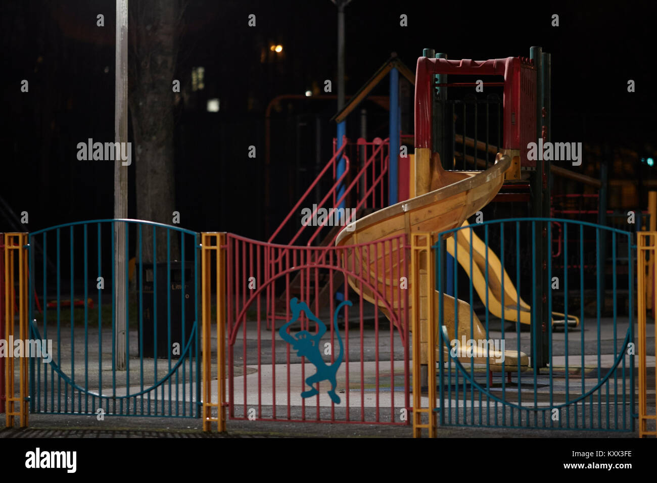 Leere beleuchtete Schieben der Kinder auf einem Spielplatz in der Nacht Stockfoto