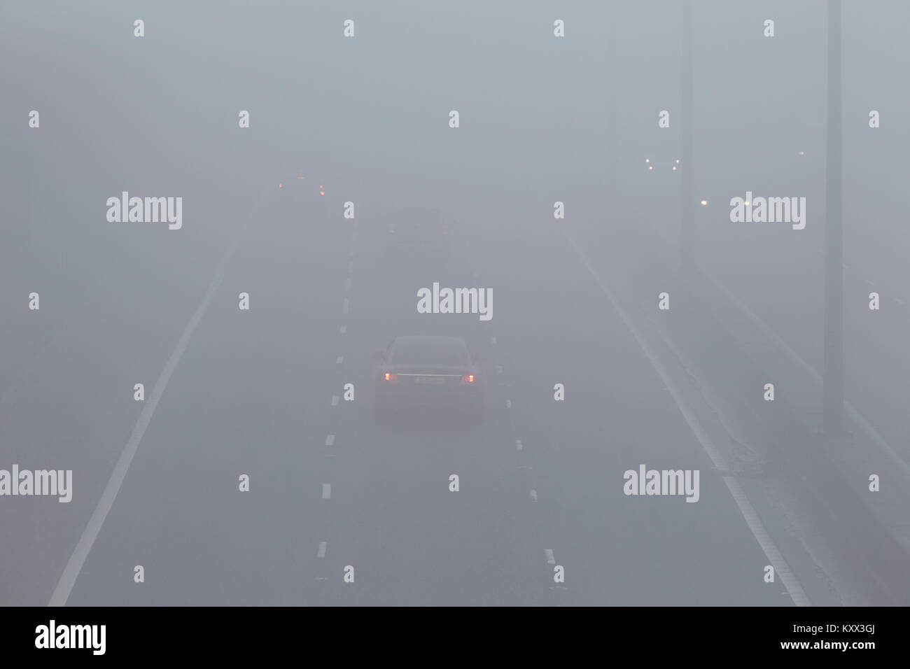 Autos fahren auf der Autobahn über foglights an einem nebligen Tag im Vereinigten Königreich Stockfoto