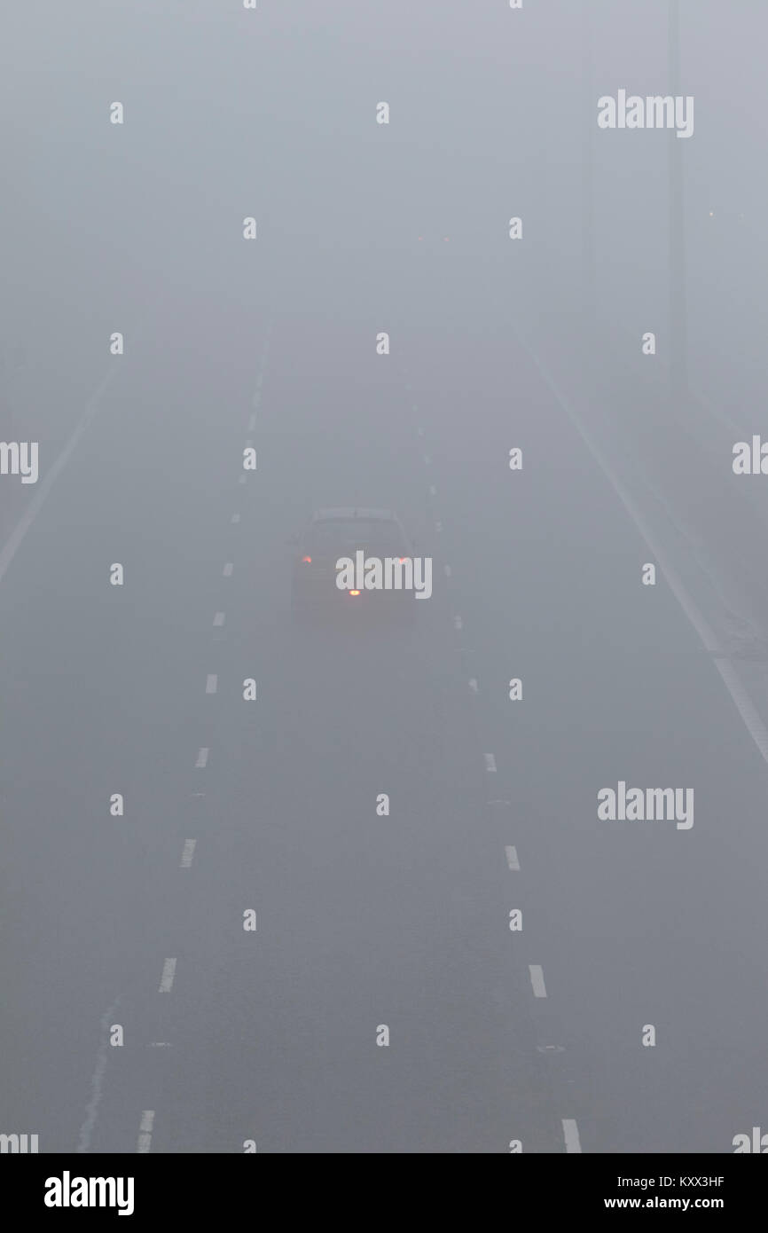 Einziges Auto fahren auf Autobahn mit Nebelscheinwerfer an einem nebligen Tag in Großbritannien beleuchtet Stockfoto