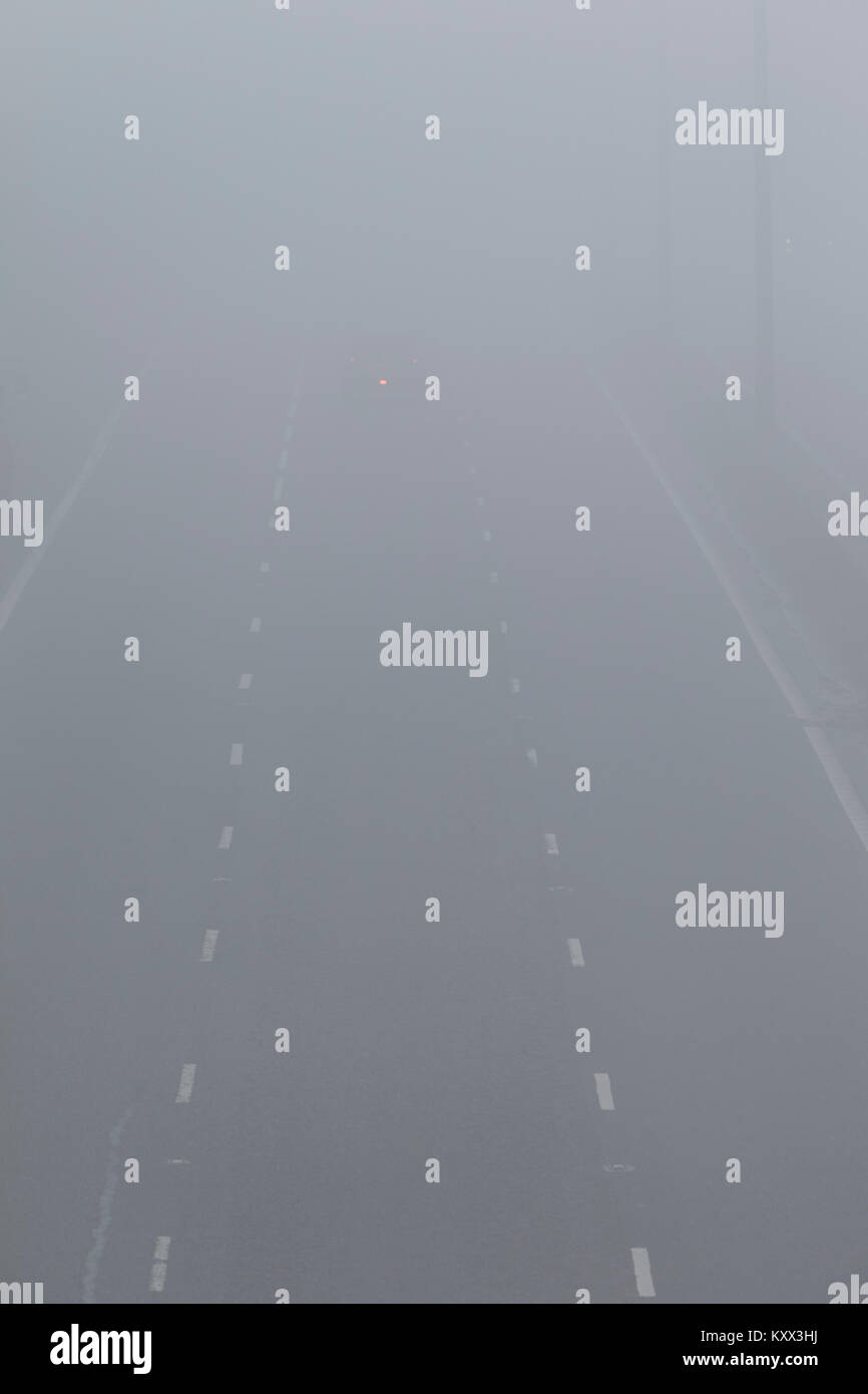 Einziges Auto fahren auf Autobahn mit Nebelscheinwerfer an einem nebligen Tag in Großbritannien beleuchtet Stockfoto