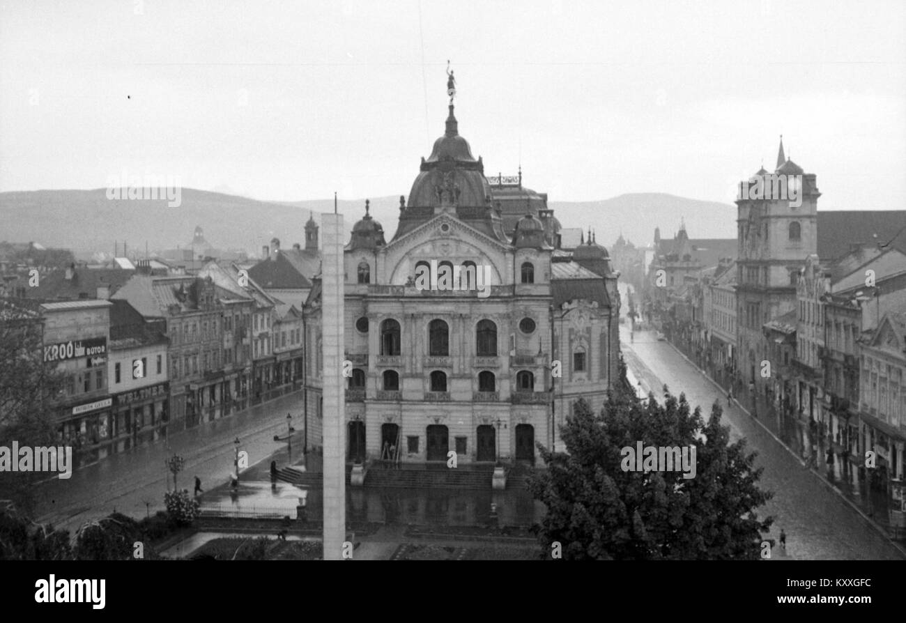 Ein historisches Foto von Fő tér (Hlavné námestie), das das Staatstheater vorne und die Dreifaltigkeitskirche rechts zeigt. Das Bild zeigt die architektonische und kulturelle Landschaft des Platzes während des frühen 20. Jahrhunderts. Stockfoto