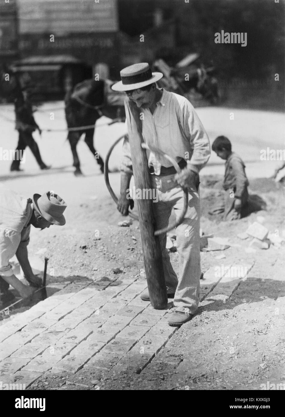 Eine Fotografie von Eugène Atget, aufgenommen um 1899–1900, die einen Straßenfertiger bei der Arbeit in Paris zeigt. Das Bild zeigt alltägliche städtische Arbeit und frühe dokumentarische Fotografie. Stockfoto