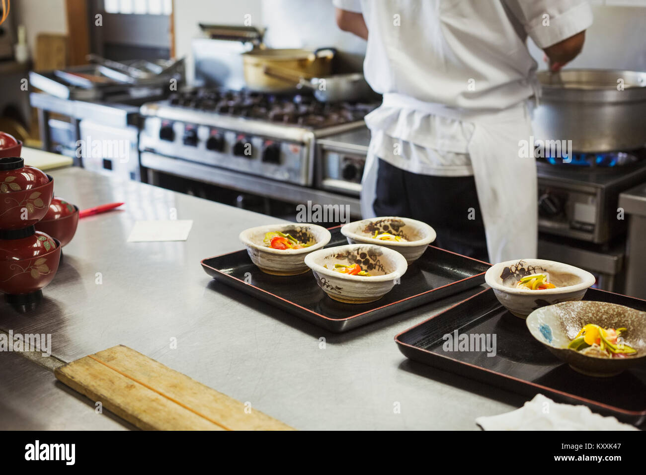 Hohe Betrachtungswinkel der Fächer mit Schüsseln von frisch zubereiteten Essen auf der Arbeitsplatte in der Küche eines japanischen Sushi Restaurant. Stockfoto