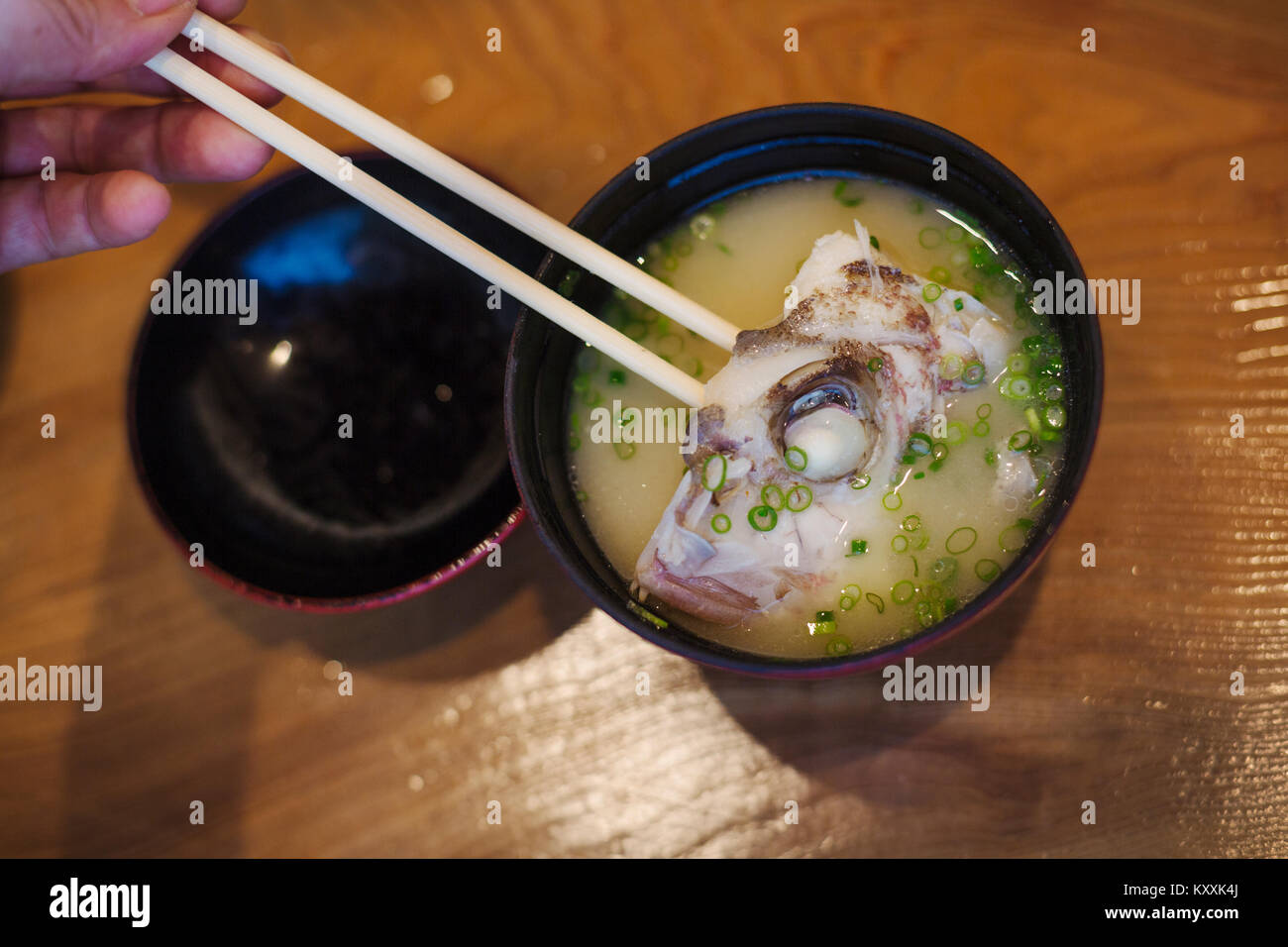 Hohen winkel Nahaufnahme von einer Schüssel mit Suppe und ein Stück Fisch in der japanischen Sushi Restaurant. Stockfoto