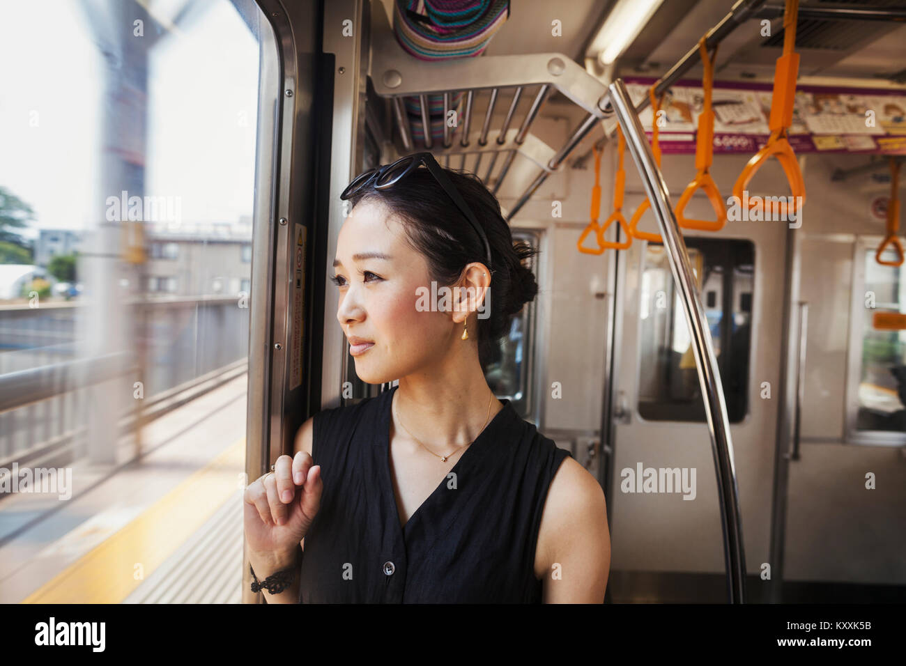 Eine Frau auf einem fahrenden Zug durch ein großes Fenster. Stockfoto