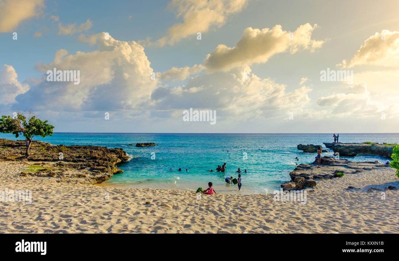Grand Cayman, Cayman Islands, Smith's Barcadere Strand in der Karibik bei Sonnenuntergang und Leute im Wasser Stockfoto
