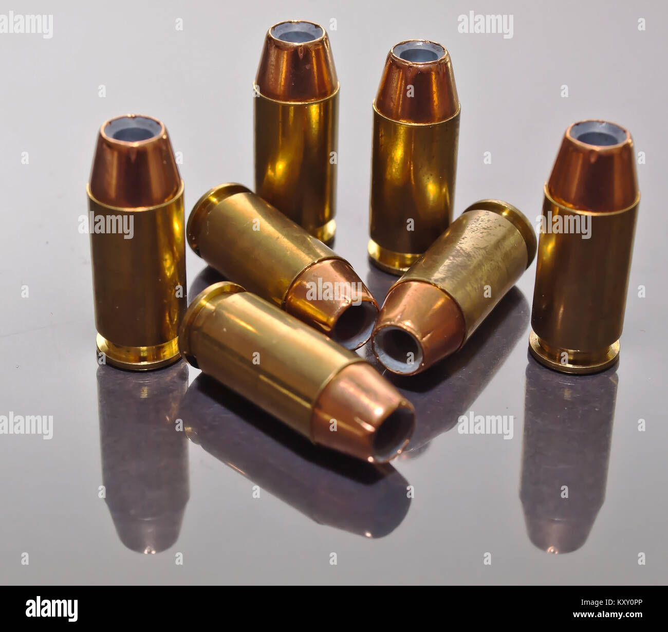 Sieben 9 mm Hollow point Bullets, mit ihren Reflexionen zusammen auf einer Glasoberfläche Stockfoto