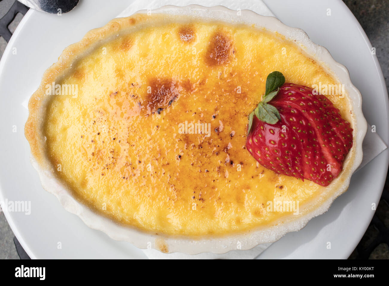 Süß und cremig Pudding Dessert aus Ei, Milch und Zucker, gekrönt mit einem in Scheiben geschnittene Erdbeeren in eine weiße Platte Stockfoto