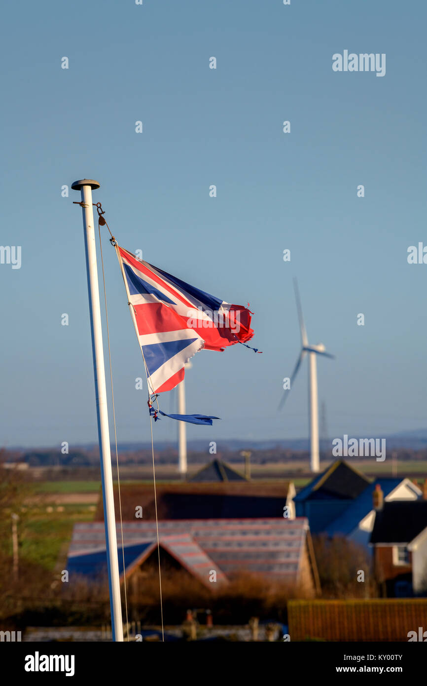 Ein tattered Union Jack Flagge im Wind flattern vor blauem Himmel. Stockfoto