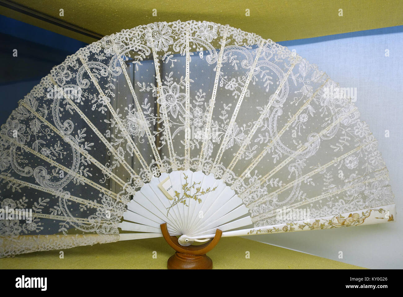 Ein europäischer Handfächer aus dem 19. Jahrhundert aus bemaltem Elfenbein, verziert mit Cupid- und Chantilly-Spitze, historisch Teil der Sammlung Alcázar von Sevilla, die dekorative Kunst und Handwerkskunst repräsentiert. Stockfoto