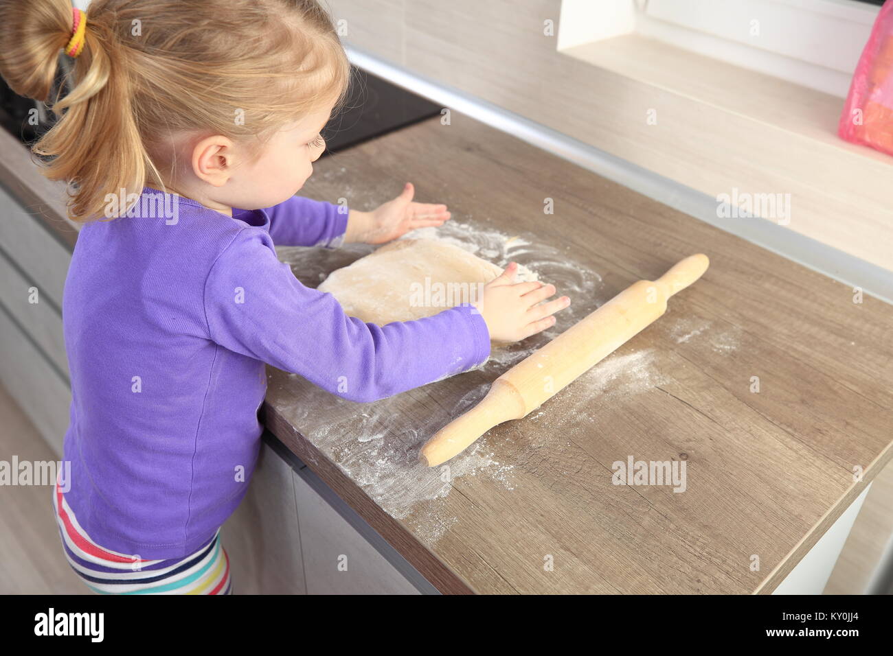 Kleines Mädchen, die versuchen, kochen backen. Kind mit Teig auf Küche. Stockfoto