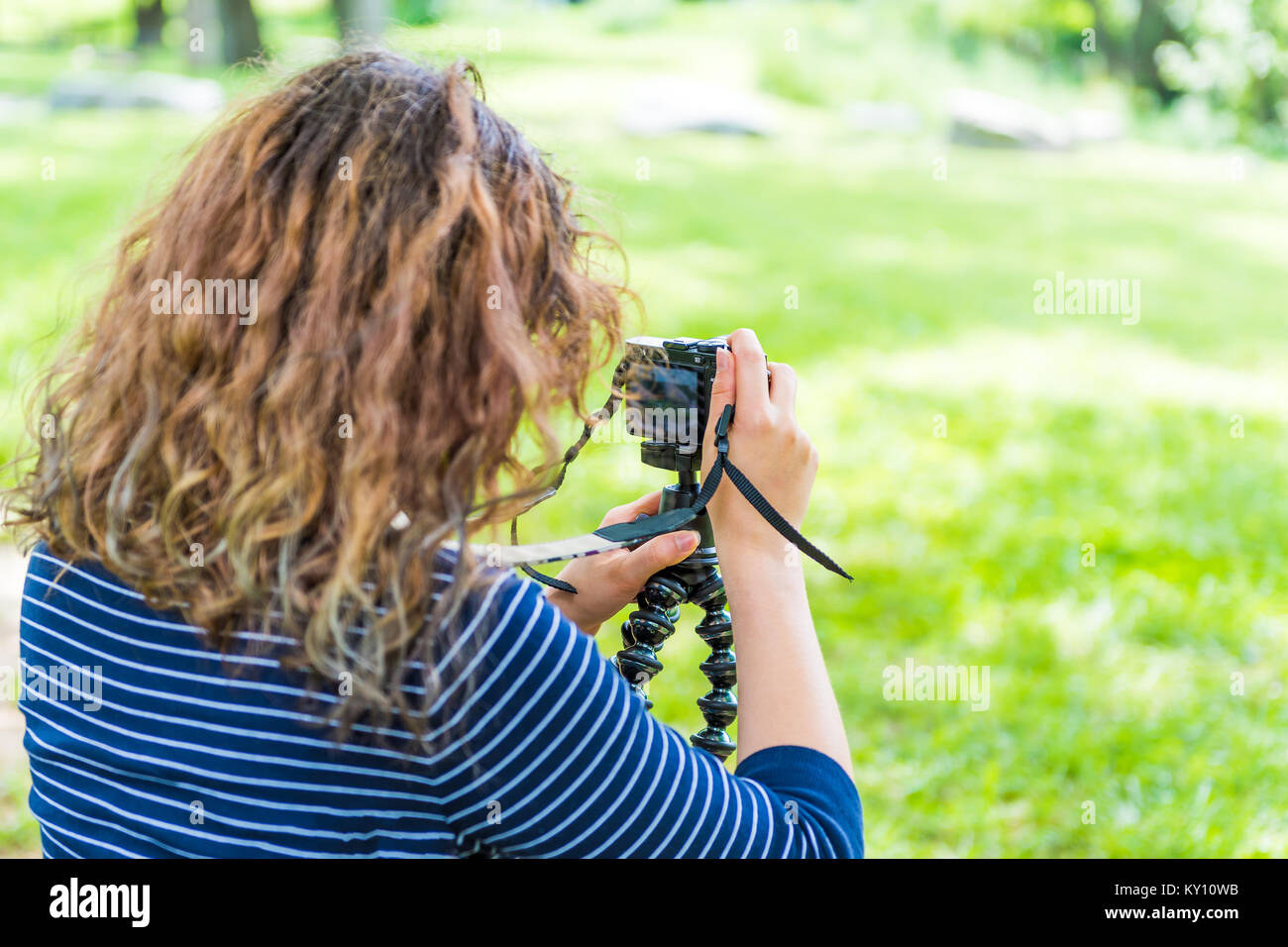 Rückseite der jungen Frau Bilder in Grün outdoor Park mit Kamera und Stativ im Sommer Stockfoto