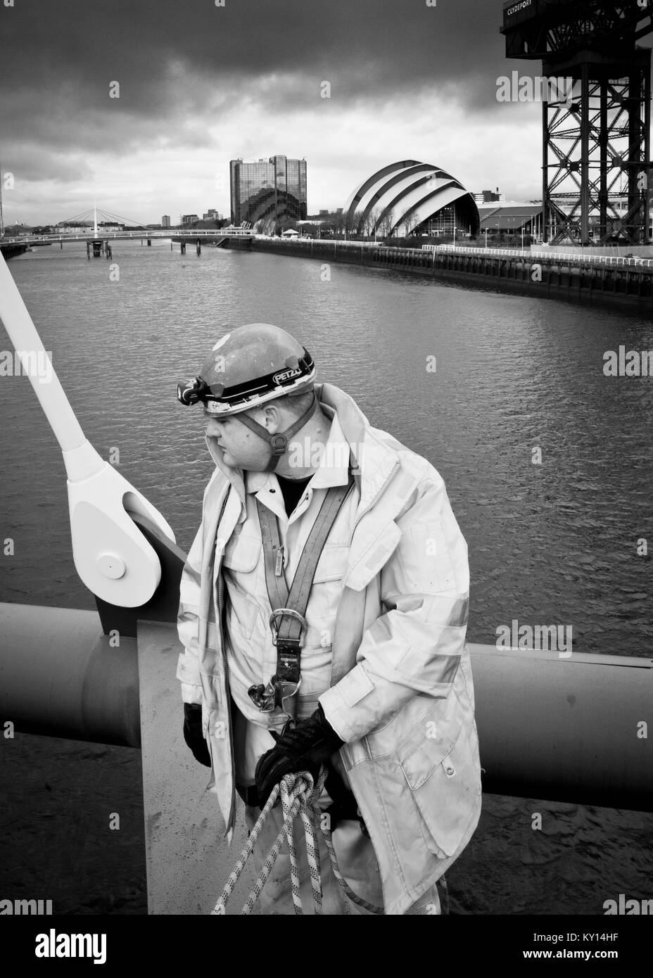 Schwarz-Weiß-Bild Nahaufnahme von Mann Seitenansicht in hoher Sicht Anzug gekleidet, stehend mit Rücken zu großen Industriekran auf dem Fluss Clyde, Glasgow. Stockfoto