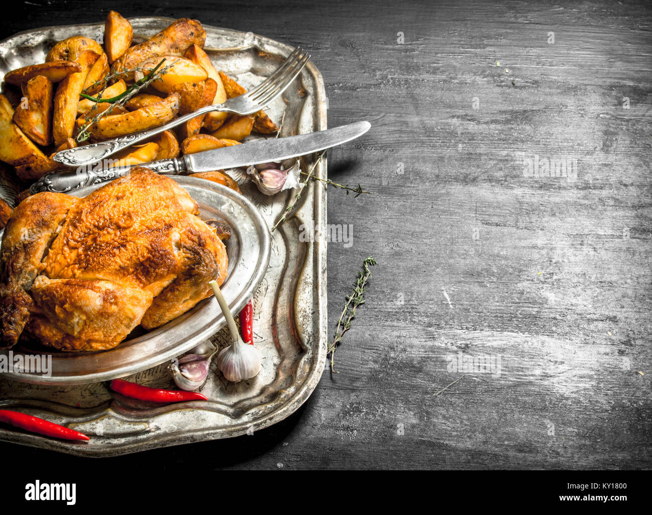 Gebratenes Huhn mit Kartoffeln auf ein Fach auf der schwarzen Tafel. Stockfoto