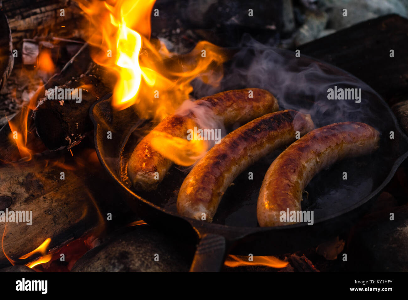 Live Feuer kochen saftigen Würstchen über dem Lagerfeuer. Stockfoto