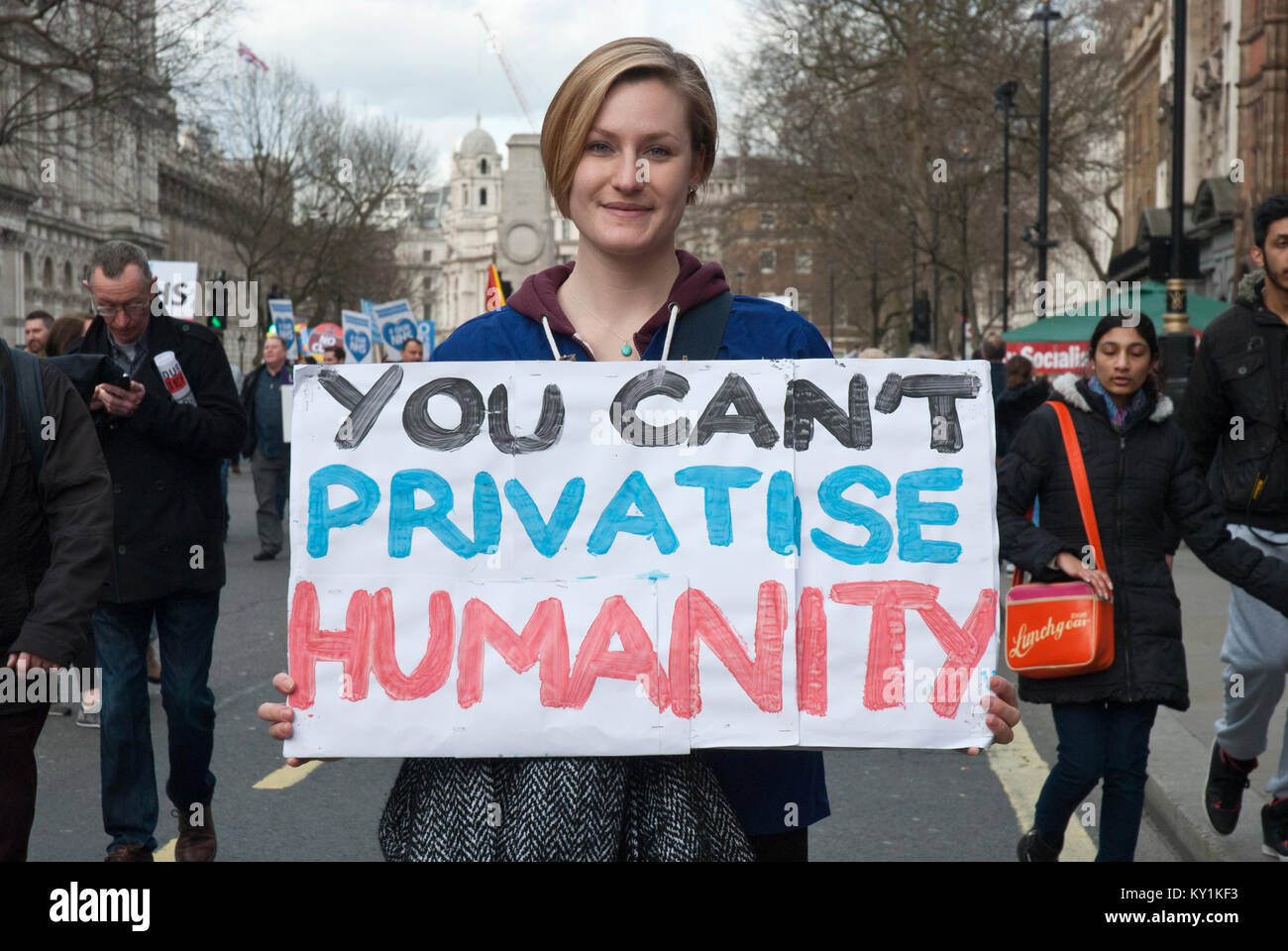 Demonstration für die NHS, eine lächelnde junge Frau, die Poster' Sie nicht die Menschheit privatisieren Ca' bezieht sich auf die Pläne der konservativen NHS zu privatisieren. London Stockfoto