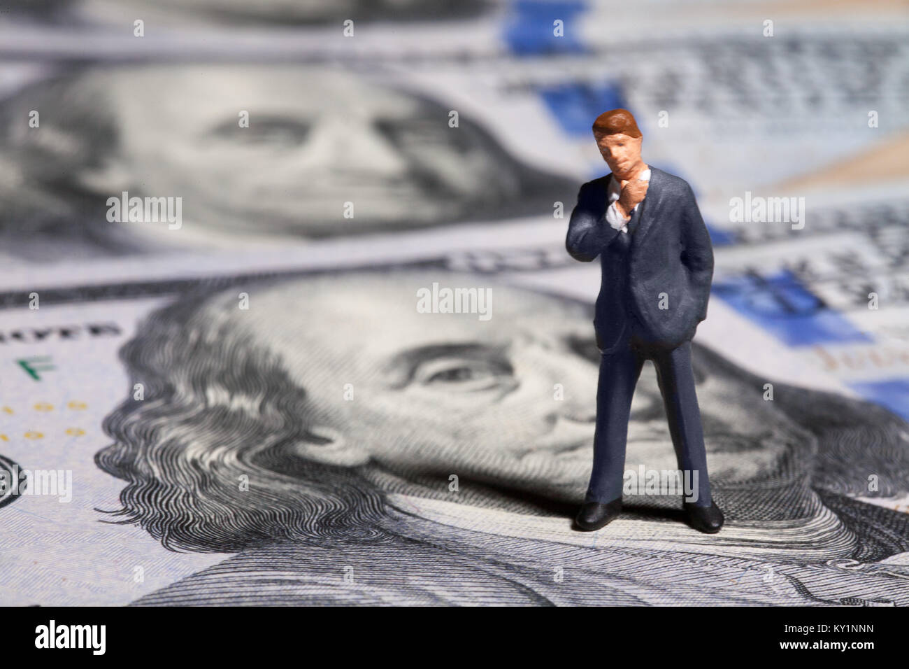 Miniatur Figur Geschäftsmann mit 100 Dollar Banknote auf Hintergrund Stockfoto