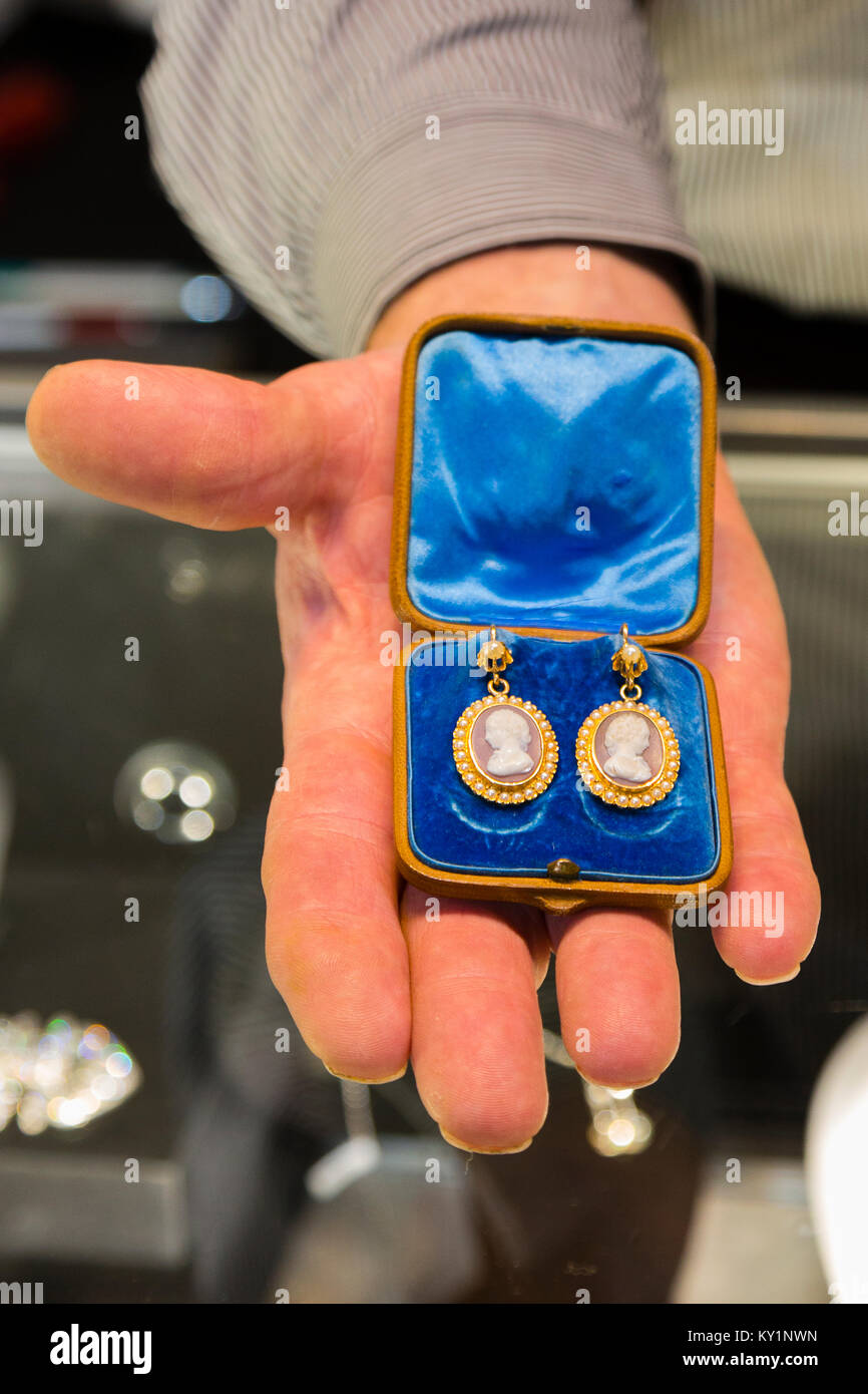 Die Kunst Antiquitäten & Interieur Messe, London, UK. Peter Beedles hält ein Paar gold Heartstone cameo Ohrringe aus den 1860er Jahren. Preis £ 4500 mit t Stockfoto
